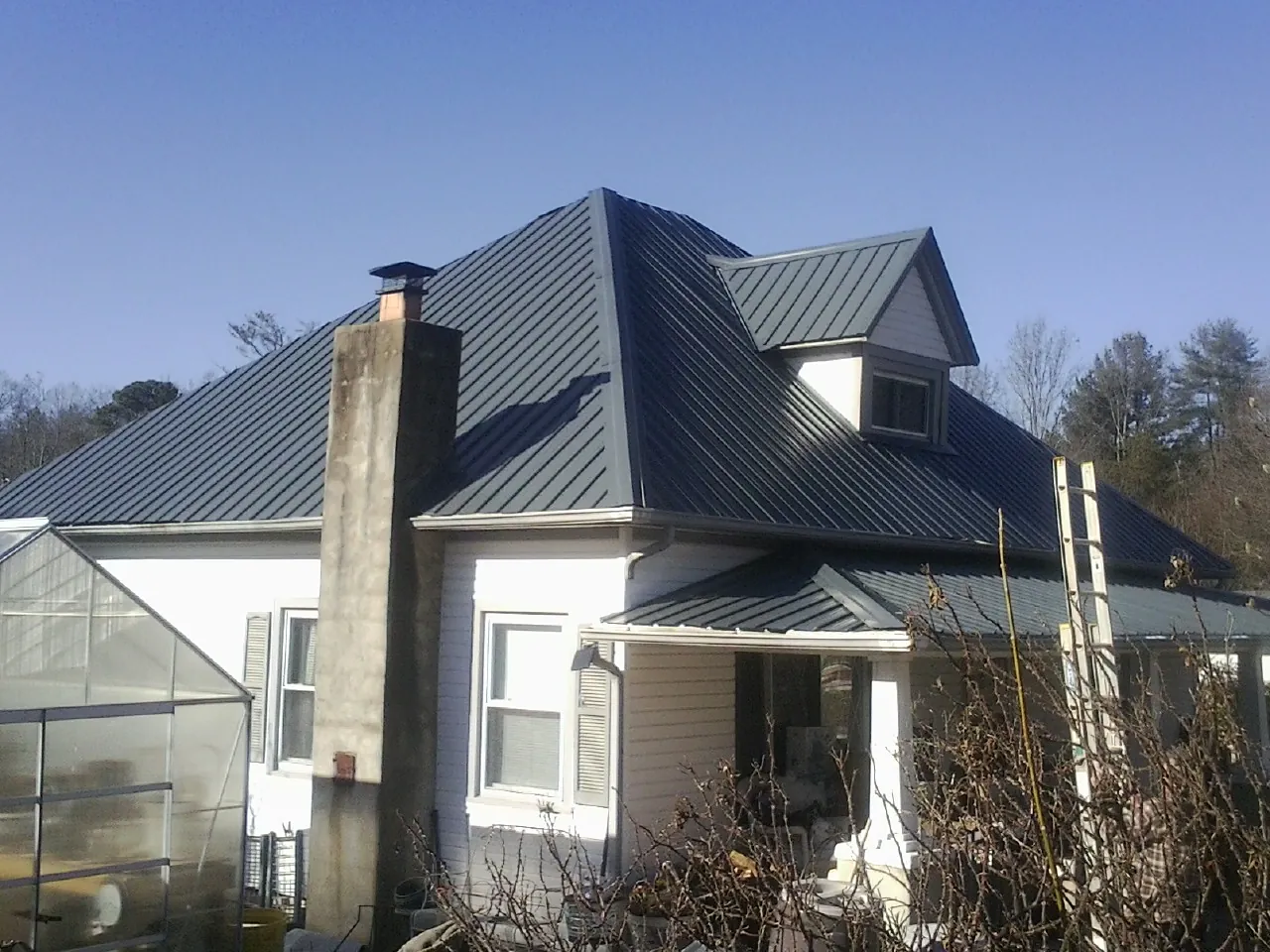 Dark blue standing seam metal roof on a white farmhouse with dormer — Slate & Tile Roof Repair by Roofing Brothers in Topsham