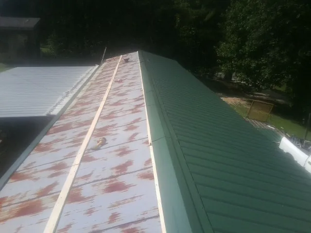 Old rusted panels beside newly installed green metal roofing — Wind Damage Roof Repair by Roofing Brothers in Topsham