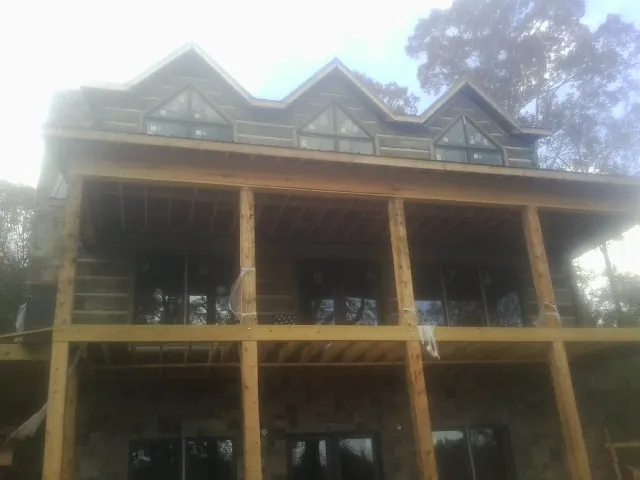 Dormers and porch framing on a large log home under construction — Roof Coating work by our crew in Topsham
