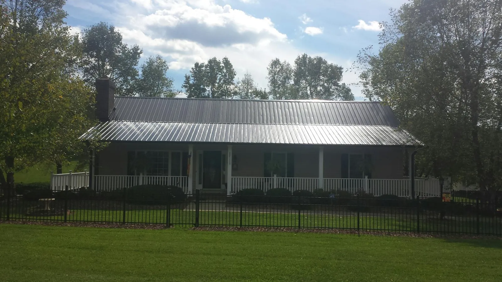 Gray metal roof on a brick ranch with a full width front porch — Gutter Guard Installation work by our crew in Topsham