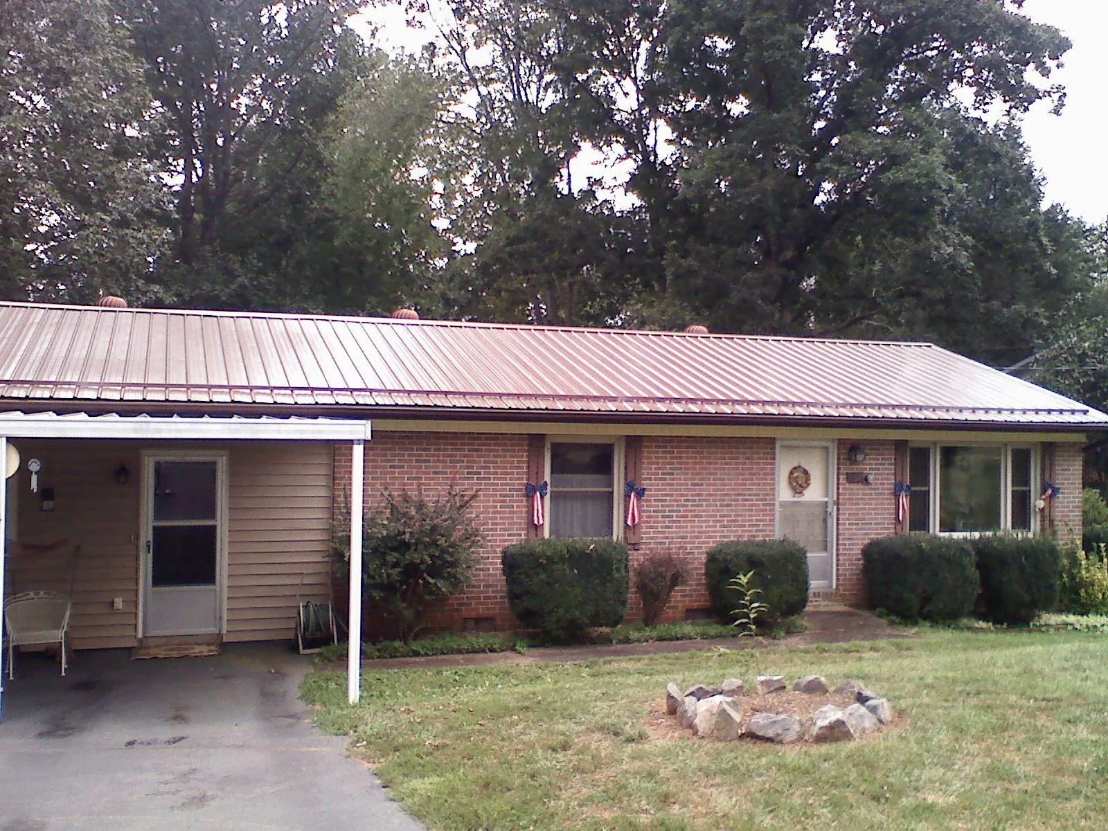 Bronze metal roof and carport on a brick ranch home — Roof Repair work by our crew in Topsham