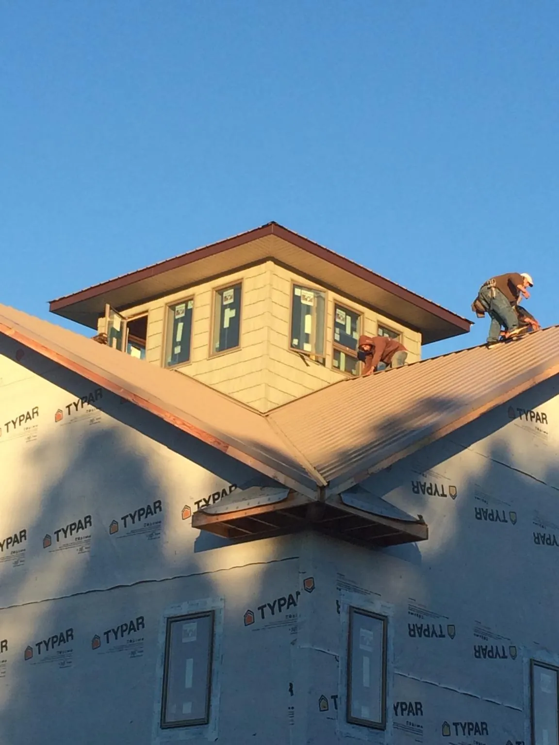 Roofers working around a rooftop cupola on a new metal roof at sunset — Roof Waterproofing in Topsham by Roofing Brothers